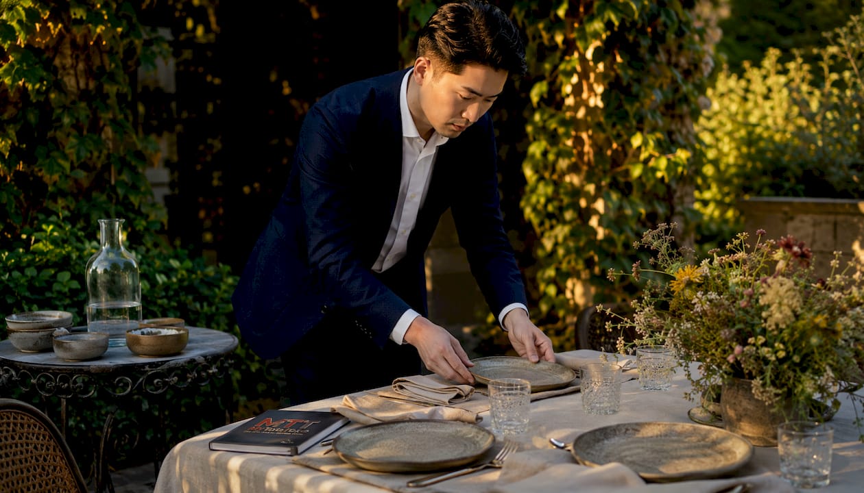 Man setting elegant, minimalist dining table