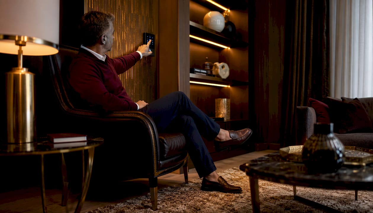 Man adjusting ambient lighting in luxury living room