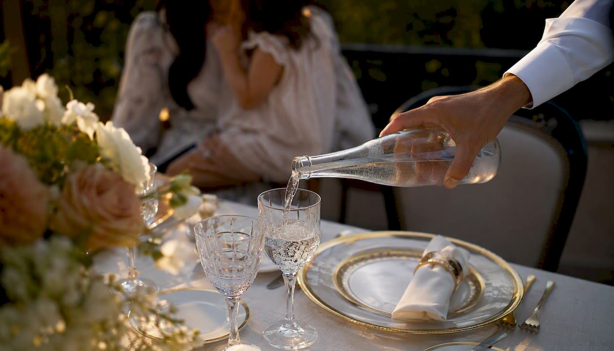 Server refilling guest's drink at luxury table