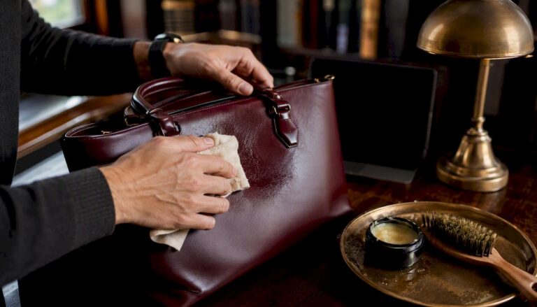 Hands conditioning a leather handbag close-up