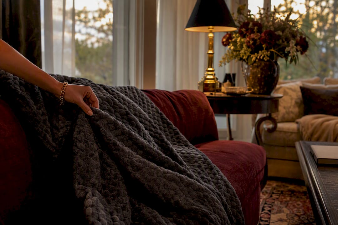 Hand adjusting weighted blanket on luxury bed