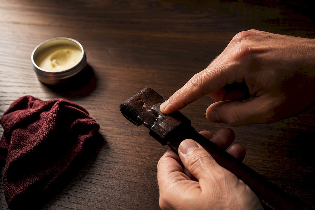 Hands conditioning a leather belt fold